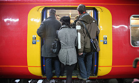 Commuters boarding vibrant train at bustling railway platform in winter weather.