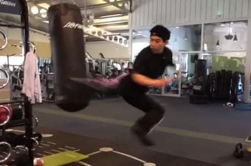 A person intensely performing a jumping exercise in a fitness facility.