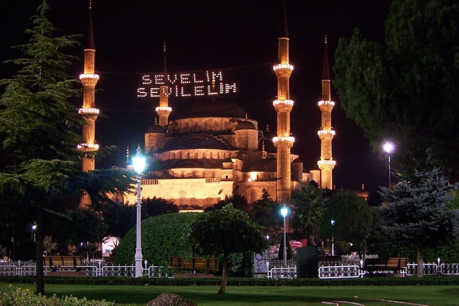 Captivating night-time view of an ornate, illuminated mosque in a tranquil garden setting.