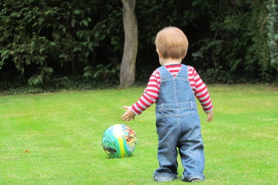 Carefree toddler explores nature with vibrant patterned football.